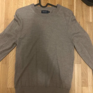 Beige tröja från Riley - Säljer en helt oanvänd stilren beige/brun tröja från Riley. Tröjan har en klassisk rund hals och långa ärmar, perfekt för en avslappnad look. Den är tillverkad i ett mjukt material som känns skönt mot huden.