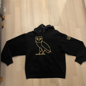 Drake: October’s Very Own - Svart hoodie med gulddetaljer - Säljer en svart hoodie från Drake’s clothing brand: October's Very Own. Hoodien köptes på en Drake konsert 2016. Är bekväm och har bra passform. Går inte att få tag på detta exemplar.