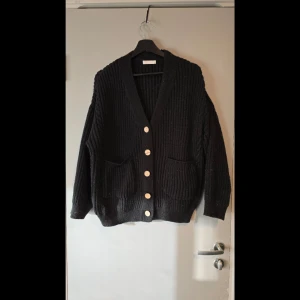 Oversized stickad kofta - Mysig svart stickad kofta med stora knappar framtill. Väldigt oversized! Hund finns i hemmet. Köpt som en S men passar definitivt större storlekar.