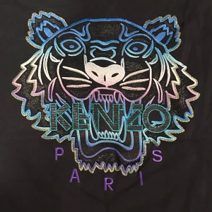 Svart t-shirt med tigerbroderi från Kenzo - Snygg svart t-shirt från Kenzo med ett stort, färgglatt tigerbroderi på framsidan. Broderiet har nyanser av blått, rosa och lila.