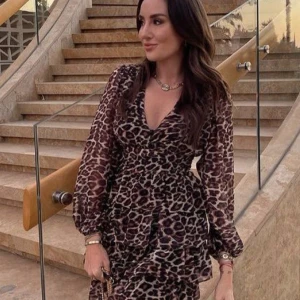 Leopardmönstrad klänning från Sisters Point - Trendig leopardmönstrad klänning från Sisters Point med v-ringning och långa ärmar. Klänningen har volangdetaljer och en omlott-design som ger en snygg passform. Perfekt för att sticka ut med stil och för resor utomlands! Knappt använd.