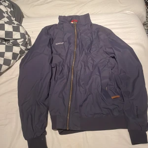 Mörkblå jacka från Didriksons - Säljer en stilren mörkblå jacka från Didriksons. Jackan har en dragkedja framtill och långa ärmar. Perfekt för kyligare dagar med sin snygga design och praktiska detaljer.