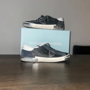 Svarta sneakers från Philippe Model - KVITTO OCH PÅSE FINNS MED.                        Snygga svarta sneakers från Philippe Model med vita detaljer och snörning. Perfekta för en stilren look.