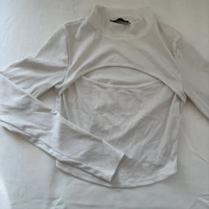 Vit ribbad polotopp - Snygg vit ribbad polotopp med lång ärm och utskärning.