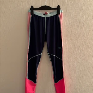 Underställ från Kari Traa  - Lleggings från Kari Traa. Mörkblå med rosa och ljusblå detaljer. Perfekta när man ska vara ute eller åka skidor! De flerfärgade i funktionsmaterial storlek M. 