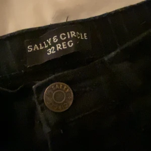 Svarta jeans från Sally & Circle - Snygga svarta jeans från Sally & Circle i storlek 32 REG. Klassisk design med knapp och dragkedja framtill. Perfekta för en stilren look.