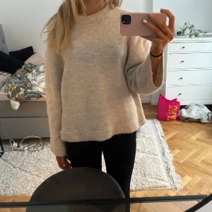 Beige stickad tröja - Mysig beige stickad tröja med rund hals och långa ärmar. Perfekt för kyligare dagar och enkel att matcha med olika outfits.