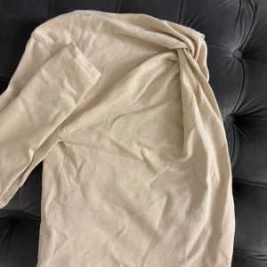 Beige långärmad tröja - Säljer en beige långärmad one shoulder tröja i mjukt material från Zara, aldrig använd och har prislapp