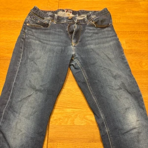 Blå jeans från Tommy Hilfiger - Snygga blå jeans från Tommy Hilfiger med klassisk femficksdesign och knappgylf. Perfekta för en avslappnad stil med en touch av elegans. Passar bra till både sneakers och kängor.