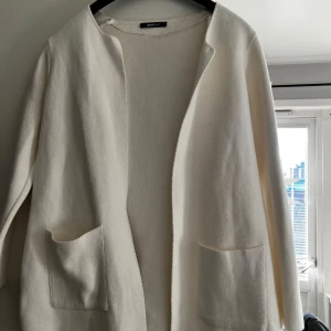 Vit kavaj från Gina Tricot - Snygg vit kavaj från Gina Tricot i en stilren design. Kavajen har långa ärmar och praktiska fickor framtill. Perfekt för en chic och minimalistisk look.