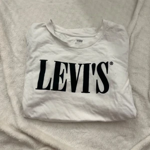 Vit t-shirt från Levi's - Säljer en klassisk vit t-shirt från Levi's med deras ikoniska logga i svart på bröstet. Betalning sker via Swish🤍 Använt 1-2 gånger, säljer då den inte kommer till användning!