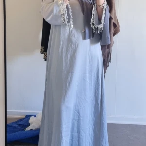 Blå blommig klänning - Charmig blå klänning med blommigt mönster. Klänningen har långa ärmar och en elegant passform som passar perfekt för vår och sommar. Den är tillverkad i ett lätt och bekvämt material. Säljer alla för 1000