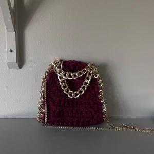 Virkad väska med silver kedja - Snygg stickad väska i vinröd och med en silver kedja. Väskan är köpt från stazzi remake. Väskan är bara använd ett fåtal gånger och är inga tecken på användning. Bilderna är lånade men de är bara att höra av sig vid frågor❣️❣️❣️pris kan diskuteras