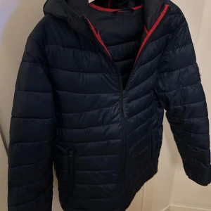 Mörkblå pufferjacka  - En riktig snygg jacka från Jack & Jones. Knappt använd så är i väldigt bra skick. Nypris: 799kr, perfekt att köpa nu inför hösten/vintern. Vid funderingar är det bara att skriva i dm! 