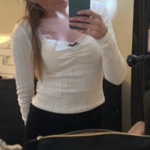 Vit ribbad långärmad topp - Säljer en stilren vit ribbad topp med långa ärmar. Toppen har en smickrande passform och en subtil v-ringning. Perfekt för en chic och enkel look.