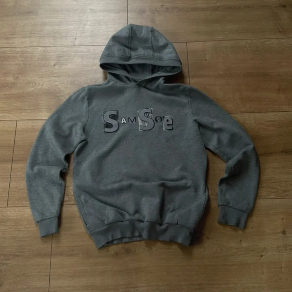 Snygg grå hoodie från Samsøe Samsøe med stor logga på framsidan. Väldigt bra skick, knappt använd✅. Neuletakit & Villapaidat.