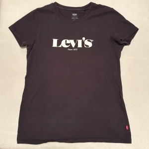 Svart t-shirt från Levi's - Använd men utan skador eller missfärgningar. Snygg svart t-shirt från Levi's med klassisk logga i vitt på bröstet. Perfekt för en casual look. Tillverkad i mjukt material för extra komfort.
