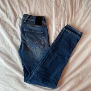 Blå jeans från Replay - Snygga blå jeans från Replay, modell Anbass. De har en klassisk femficksdesign och en bekväm passform. Perfekta för en stilren look.