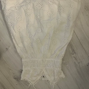 Vit broderad klänning - Charmig vit klänning med broderade blommönster och spetsdetaljer.