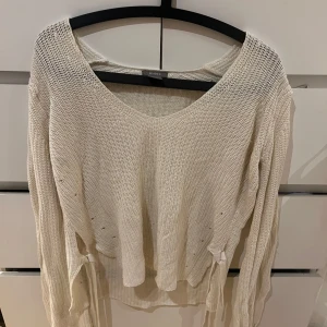 Vit stickad tröja från Lindex - Säljer en vit stickad tröja från Lindex med v-ringning. Tröjan har en avslappnad passform och långa ärmar, perfekt för kyligare dagar. Man kan knyta den snyggt på båda sidor! Köpte den för 399kr säljer den för 150+frakt. Passar även de som har M.