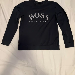 Mörkblå Hugo Boss Sweatshirt Storlek Large  - En mörkblå Hugo boss sweatshirt med silvrigt tryck på bröstet som är i storlek large, sweatshirten är i bra skick. Tveka inte på att höra av dig om du är intresserad eller om du har några frågor!