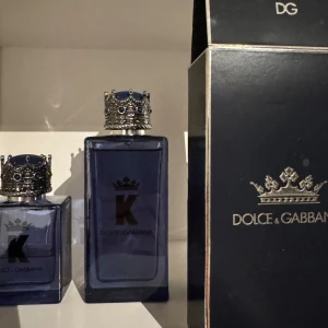 Dolce & Gabbana K  - Säljer en elegant Dolce & Gabbana K Eau de Toilette i en stilren blå flaska med en unik kronformad kork. Perfekt för den som vill ha en sofistikerad och maskulin doft. Flaskan har en modern design som utstrålar lyx och stil.