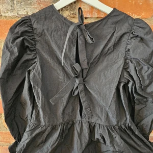 Blus med knyte i ryggen - Jättefin svart blus ned knyte i ryggen stl.XS från H&M Divided. Kan skickas mot porto alt hämtas i Sjöbo, Malmö eller Lund.