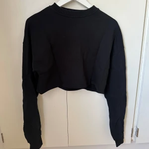 Sweatshirt - Croppad svart sweatshirt med tryck på ryggen från NA-KD, i bra skick!