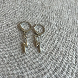 Silverörhängen med blixtmotiv - Säljer ett par coola silverörhängen med blixtmotiv. De är i nyskick och perfekta för att ge din outfit en edgy touch. Passar både till vardags och fest!