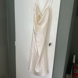 Kort satin klänning - Kort satin klänning med korsade band över ryggen, ingen dragkedja, krämvit🌟 Nyskick utan prislapp, storlek 38/M💗 Tryck gärna på köp nu