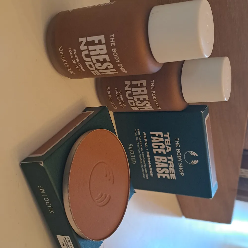 Säljer två flaskor av The Body Shop Fresh Nude Foundation, 30 ml vardera, i en naturlig nyans. Perfekt för en fräsch och jämn hudton. Dessutom ingår ett Tea Tree Face Base puder, 9 g, som ger en matt finish och hjälper till att klargöra huden. Båda produkterna är idealiska för daglig användning och ger en naturlig look.. Skönhet.