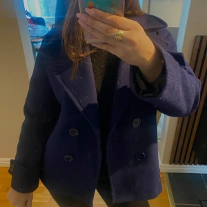 Kappa från design by si - Vacker mörkblå peacoat från design by si i hög kvalitet, med fyra eleganta svarta knappar. Kappan är både stilren och varm, perfekt för hösten. Den har en klassisk design som passar till både vardag och fest. Tryck ej ”köp” innan vi diskuterat.