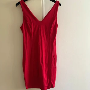 Röd klänning med v-ringning - Snygg röd klänning med v-ringning och ärmlös design. Perfekt för festliga tillfällen. Klänningen har en tight passform som framhäver figuren. Den är gjord i ett mjukt och bekvämt material som känns skönt mot huden. En riktig blickfångare för kvällen! 💃