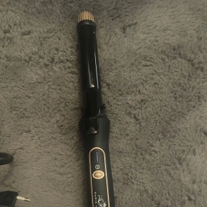 Svart locktång från Paris Hilton - Säljer en elegant svart locktång från Paris Hilton med guldiga detaljer. Den har en sladd med EU-kontakt och en enkel on/off-knapp. Perfekt för att skapa snygga lockar till både vardag och fest! 🌟