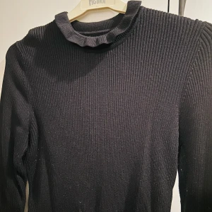 Svart ribbad tröja från Gina Tricot - Säljer en stilren svart ribbad tröja från Gina Tricot i storlek L. Tröjan har långa ärmar och en fin rynkad krage som ger en extra touch. Perfekt för både vardag och fest! 🖤