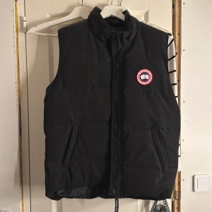 Canada Goose Väst - Säljer denna väst från Canada Goose. Knappt använda men skulle säga att den är liten i storlek så passar en som har L men även nån som har M!😇  Om ni har frågor eller så hör av er jackan passar både tjej och kille!💗