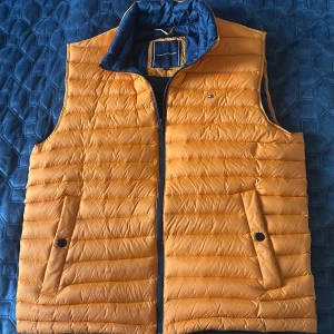 Tommy Hilfiger väst - Säljer en helt ny Tommy Hilfiger höstväst i storlek L för herr. Perfekt för svala höstdagar, kombinerar stil och funktion med den klassiska Tommy Hilfiger-designen. Ser ut att vara ljus blå i bilen, fast det är marin blå.