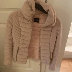 Ljus rosa  jacka från Guess - Säljer en superfin beige  jacka från Guess. Den har en snygg dragkedja framtill och två dragkedjefickor på sidorna. Jackan är perfekt för höst och vår, och den har långa ärmar med dragkedjor vid ärmsluten. Den är i nyskick och väldigt bekväm. 