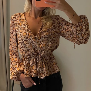 Blus i ormmönster Mango - Säljer denna såå snygga blus i ormmönster och knytning i midjan från Mango! Nyskick💘 storlek M