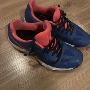 Blå och rosa Asics träningsskor - Säljer ett par Asics träningsskor i blått och rosa. De har en snygg design med svarta snören och en vit sula. Perfekta för träning eller löpning. Skorna är i bra skick och redo för nya äventyr!