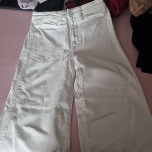 Vita culotte jeans - Säljer ett par vita culotte jeans i storlek 34. De är högmidjade och har en loose fit som ger en avslappnad och trendig look. Perfekta för både vardag och fest!