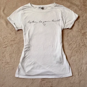 Vit t-shirt med text - Vit t-shirt med text, lös passform. Använd fåtal gånger, bra skick strl XS.
