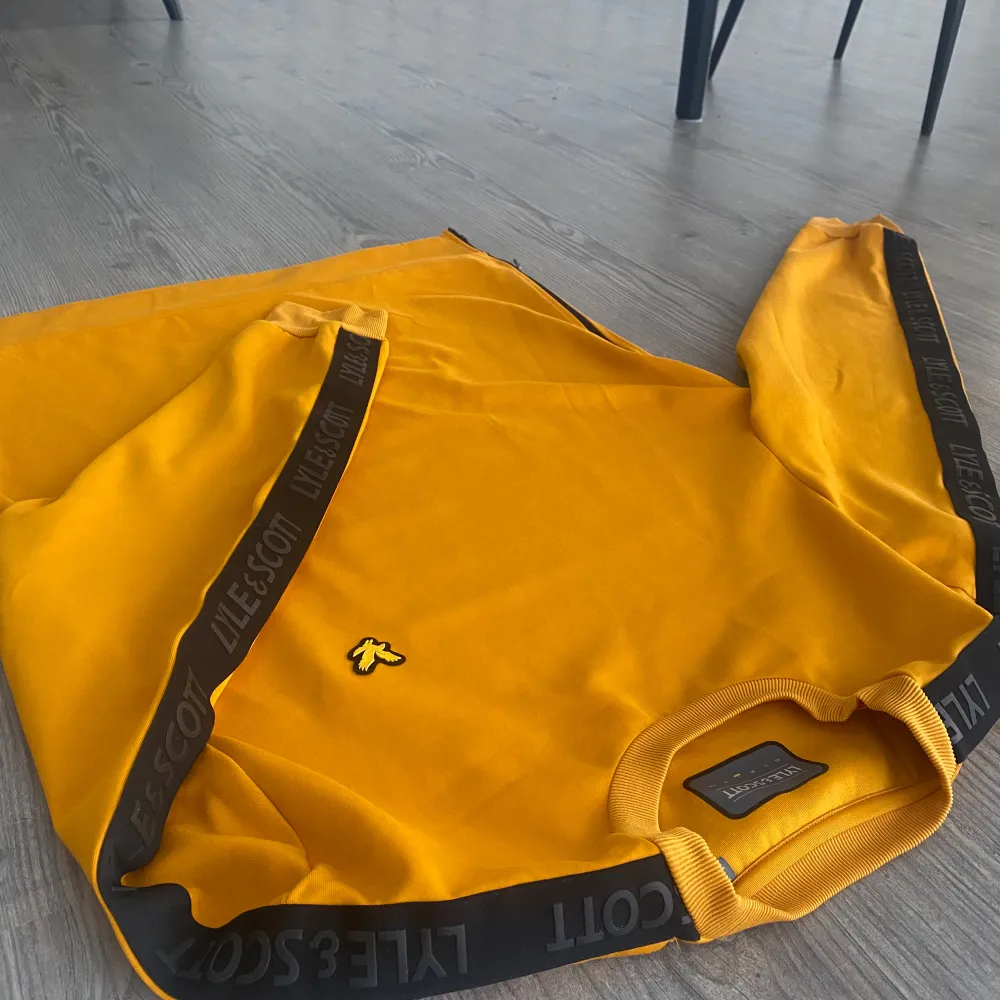 Säljer en snygg gul tröja från Lyle & Scott med svarta detaljer längs ärmarna. Tröjan är helt o använd vilket kan ses på bilderna, skriv om ni funderar på något!. Neuletakit & Villapaidat.