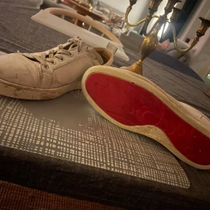 Vita sneakers med röd sula - Snygga vita sneakers med den ikoniska röda sulan. Skorna har snörning och är tillverkade i skinn. Perfekta för en stilren look. Skorna är inte köpta i affär så är inte helt 100% säker på äktighet, kan gå ner i pris vid snabb affär🤝box medföljer mee massor av olika kvitton, det finns  smuts på skon men går säker bort med vatten o en borste 