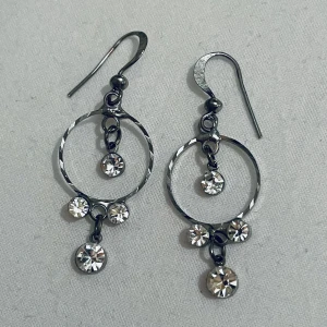 Silvriga örhängen med glittriga stenar - Snygga silvriga örhängen med cirkelformad design och hängande glittriga stenar. Perfekta för att ge en extra touch av glamour till din outfit. De har en krok för enkel användning.