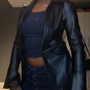 Svart skinnjacka - Snygg svart skinnjacka med knappar och figurnära passform. Perfekt för en stilren look.