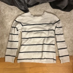 Vit och svart randig tröja - Säljer en stilren vit tröja med svarta ränder. Tröjan har långa ärmar och en klassisk rund hals. Perfekt för en avslappnad look.