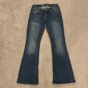 Blå bootcut jeans från Detroit - Snygga blå bootcut jeans från Detroit med hjärtbroderi på bakfickorna. De har en klassisk femficksdesign och en bekväm passform. Perfekta för en avslappnad stil.