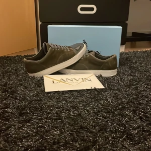 Oliv gröna Lanvins - Snygga oliv gröna sneakers från Lanvin med en stilren design. Skorna har en blank tå och en klassisk snörning, vilket ger en elegant touch. Perfekta för en trendig look. 9/10 i skick. 2 små dustbags och en stor. Även ett kuvert från lanvin ingår. Vid frågor är det bara att höra av sig!