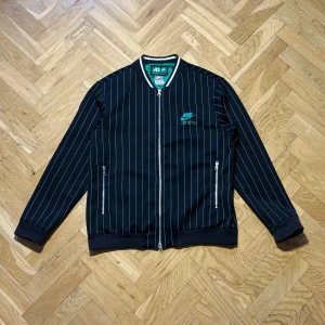 Vintage retro 00s/90s Nike varsity jacket - Snygg svart jacka/tröja från Nike med vita ränder och grönt foder. Jackan är i mycket bra skick storlek large